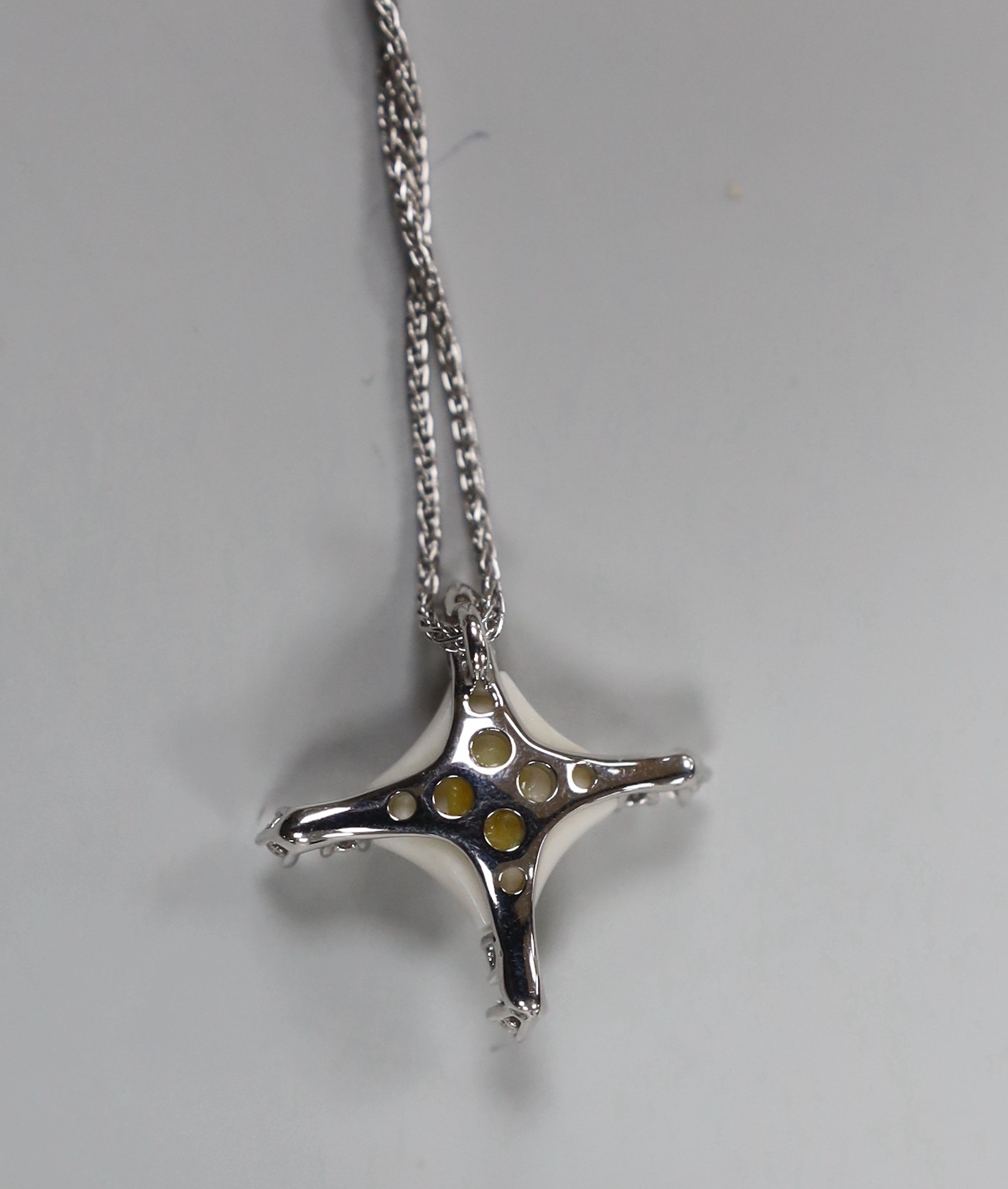 A modern Italian Roberta Porratti 18k white metal, six stone diamond and ceramic? set quatrefoil pendant, 23mm, on an 18k white meal chain, 40cm, signed, gross weight 7.5 grams.